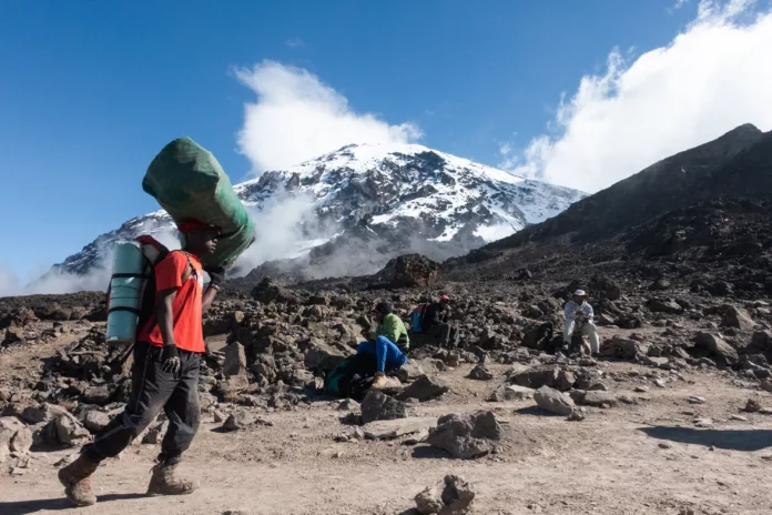 Einheimische Träger mit Kilimanjaro im Hintergrund