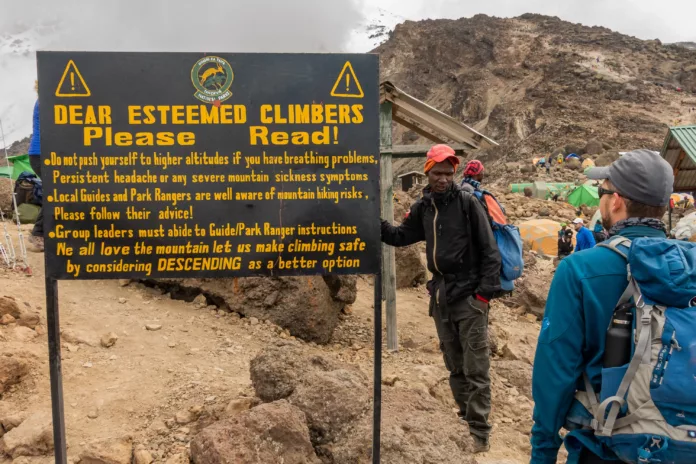 Schild über Höhenkrankheit im Barafu Camp mit Bergsteiger