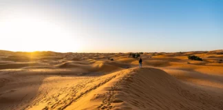 Mädchen auf einer Düne in der Erg Chebbi Wüste bei Sonnenaufgang