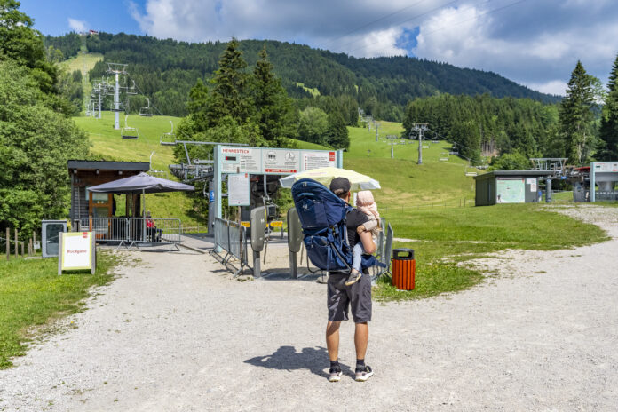 Vater mit Kind in Kraxe am Sessellift Annaberg