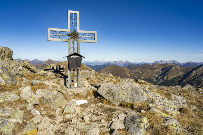 Das Gipfelkreuz des Pletzen, im Hintergrund die Gesäuse-Berge